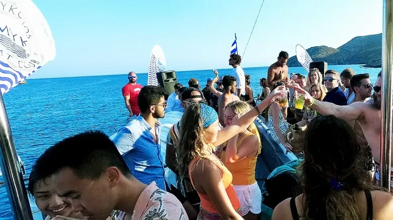 Festa no barco por Mykonos ao entardecer